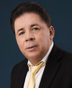 Lic. Julián Solano, sentado con saco oscuro, camisa blanca y corbata amarilla