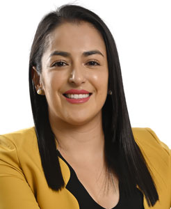 Licda. Susana Sotelo, cabello largo, negro, vestido con saco de color amarillo, mirando con una sonrisa hacia el frente